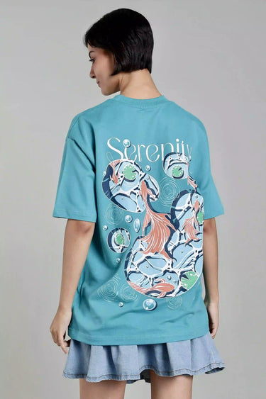 Back view of a woman wearing a teal fish t-shirt with a fish design on the back against a gray background