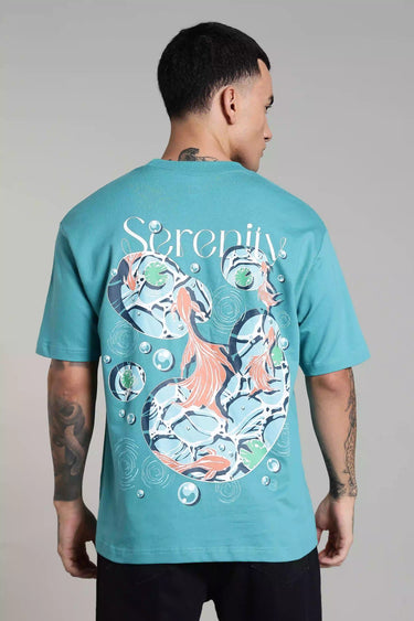 Back view of a man wearing a teal fish t-shirt with a fish design on the back against a gray background
