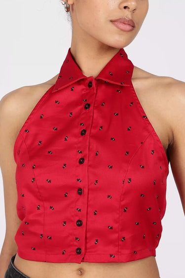 A close-up shot of a Red halter printed cropped shirt with black button details on a white background