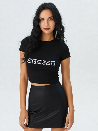 Woman wearing a black crop top with 'SHEESH' text and a black skirt on a white background