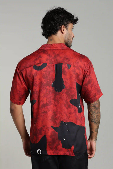 backview of a man wearing a red shirt with black cow patterns on a gray background