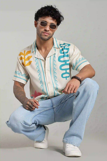 Man wearing an OASIS PRINTED shirt and light blue jeans on a gray background