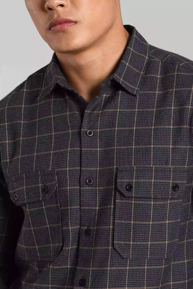 Close-up of a person wearing a checked shacket against a gray background