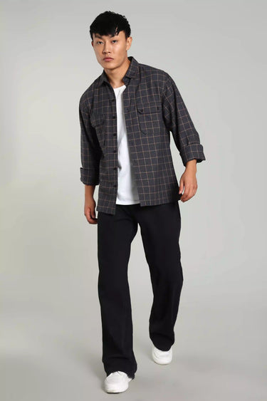 Man wearing a Navy Blue Brushed Yarn Dyed Checked Shacket, a white t-shirt underneath, black pants, and white sneakers on a gray background