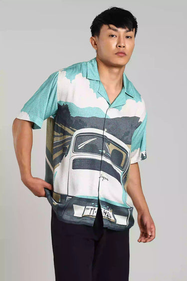 Model wearing a BON VOYAGE SHIRT featuring a vintage car and scenic landscape, perfect for wanderlust enthusiasts.