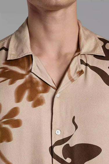 Close-up of a beige boho shirt with brown floral patterns on a gray background