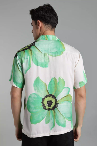 Man wearing a white shirt with green floral patterns on a gray background