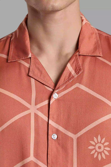 Close-up of a person wearing a brown tile patterned shirt with a gray background