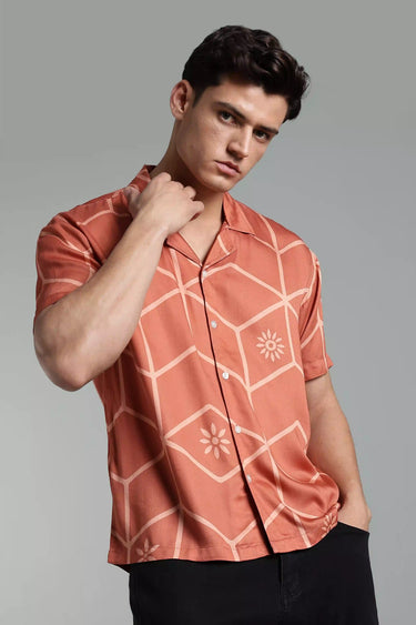 A man wearing a brown tile-patterned shirt against a gray background