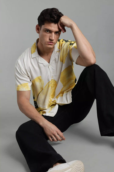 Man wearing a Yellow Floral Print Shirt for Men and black pants sitting on a gray background