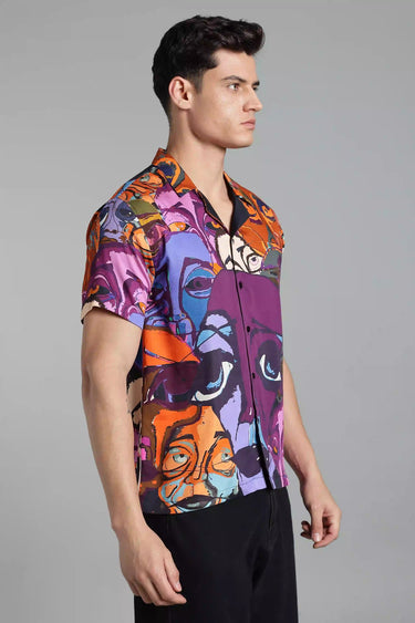 A man wearing a colorful abstract design shirt on a gray background