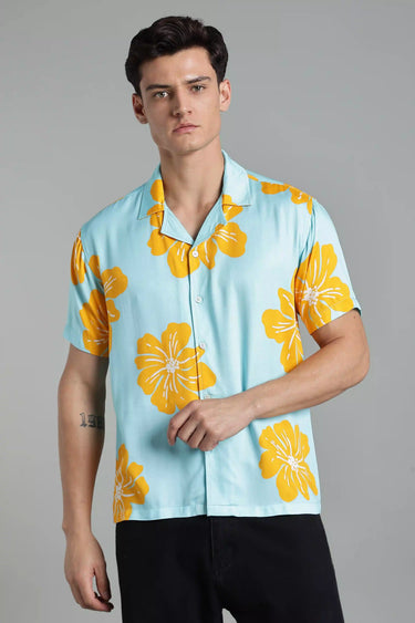 Man wearing a light blue shirt with yellow floral patterns on a gray background