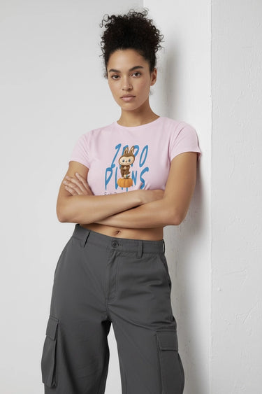 Pink graphic crop top with colorful monster print and short sleeves worn with gray pants. - LYVN