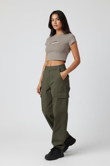 Woman wearing a dark beige graphic crop top and green cargo pants on a white background