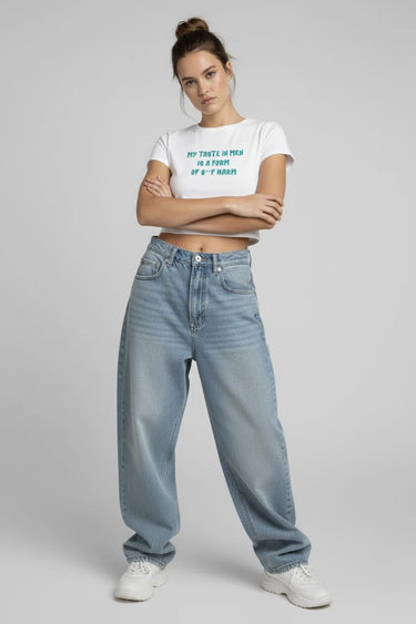 Person wearing a white crop top and light blue jeans on a gray background