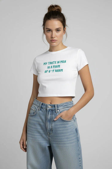 Woman wearing a white crop top with text and blue jeans on a plain background