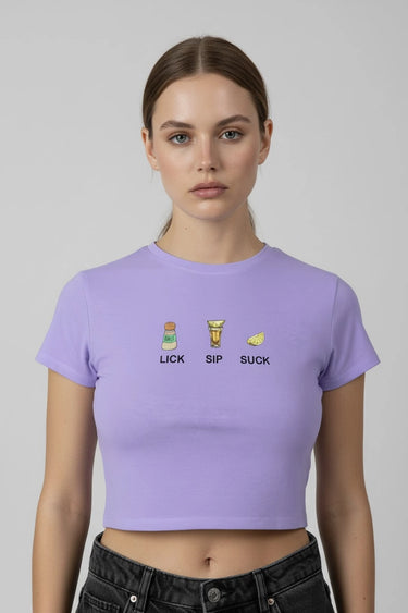 Person wearing a purple crop top with graphic designs and text that says "LICK SIP SUCK" on a plain background
