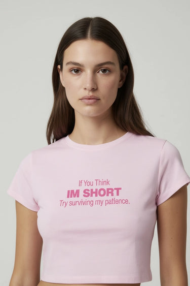 Person wearing a pink crop top with humorous text on a plain background