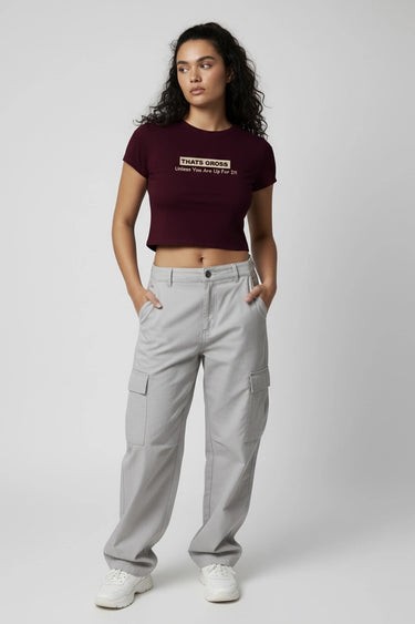 Woman wearing a maroon crop top and gray cargo pants on a grey background