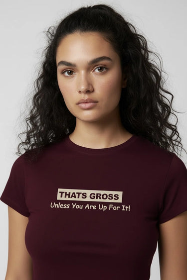 Woman wearing a maroon graphic crop top with text on a plain background