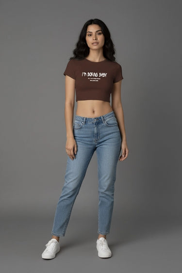 Brown graphic crop top with "I'm Boring Baby" text paired with light blue jeans and white sneakers.