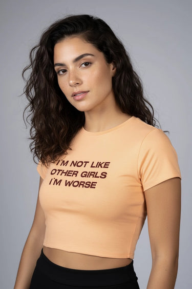 Woman wearing an orange graphic crop top with text on a gray background