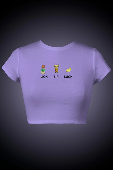 Purple graphic crop top with text that says "LICK SIP SUCK"and graphics on a dark background