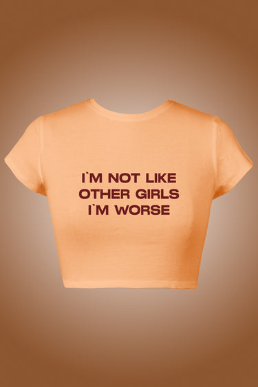 Peach short-sleeve graphic crop top with bold brown text "I'M NOT LIKE OTHER GIRLS I'M WORSE".