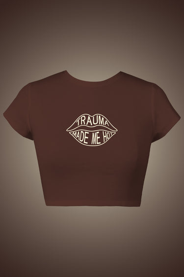 Brown short-sleeve graphic crop top with white "TRAUMA MADE ME" lip design on front.