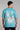 Back view of a man wearing a teal fish t-shirt with a fish design on the back against a gray background