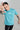 A man wearing a teal fish unisex oversized t-shirt with a logo, making a stop gesture against a gray background
