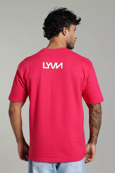 Bright pink, oversized graphic t-shirt featuring a white "LYVN" logo on the back, styled by a male model. - LYVN