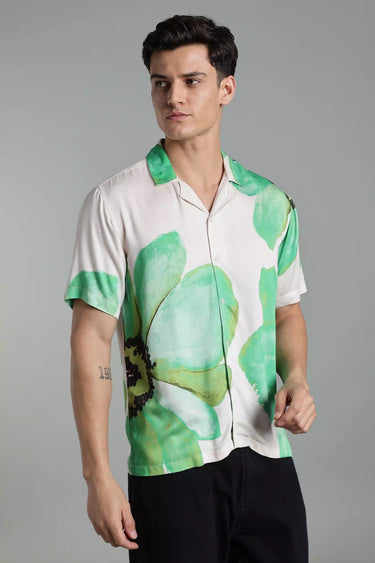 Man wearing a white shirt with green floral patterns on a gray background