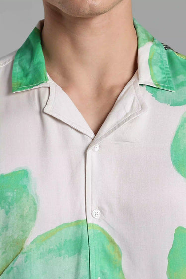 Close-up of a person wearing a white shirt with green leaf patterns on a gray background