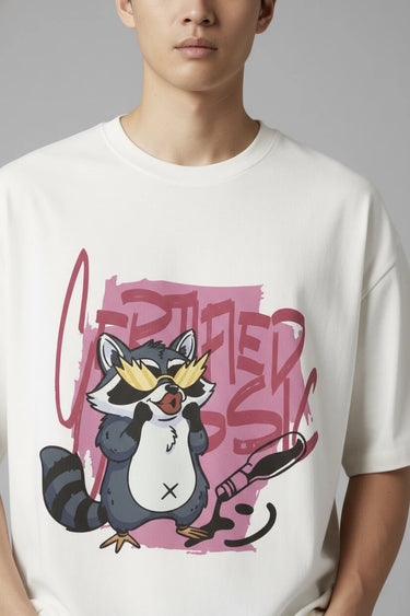 Person wearing a half white unisex oversized t-shirt with a cartoon raccoon design and text.