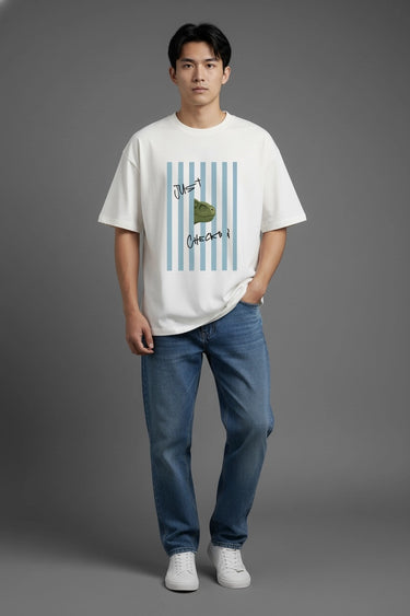 Person wearing a half white unisex oversized  t-shirt with a graphic design on a gray background