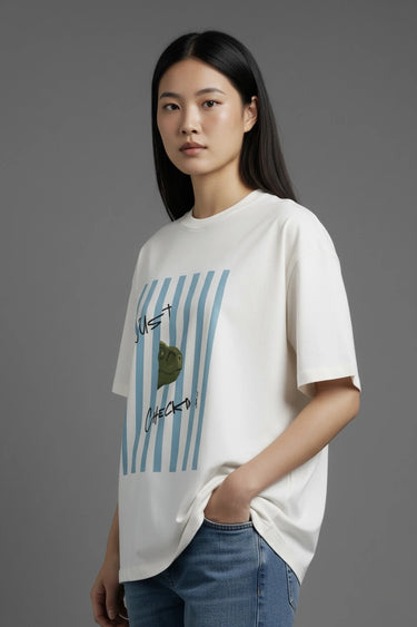 Woman wearing a half white unisex oversized  t-shirt with a graphic design on a gray background