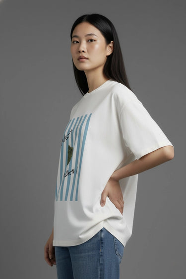 A woman wearing a half white unisex oversized  t-shirt with a graphic design on a gray background