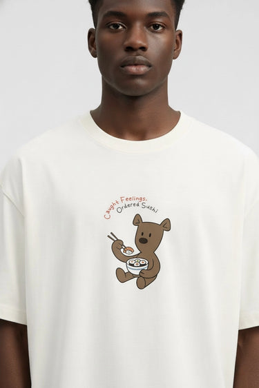 Person wearing a white unisex oversized t-shirt with a bear graphic and text on a plain background