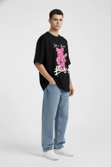 Black oversized graphic t-shirt with pink jelly baby design and white text, paired with light blue jeans.