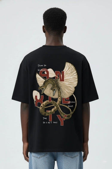 Person wearing a black unisex oversized t-shirt with a snake and eagle graphic on the back, standing against a white background.