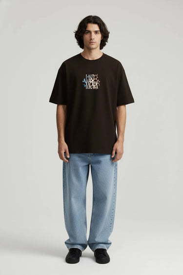 Black oversized graphic t-shirt with multicolor "Last Known" text design, paired with light blue jeans.