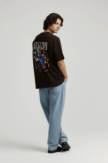 Black oversized graphic t-shirt with colorful skeleton design on back, paired with light blue pants and black shoes.