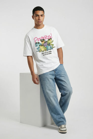White oversized graphic t-shirt with colorful cartoon print and loose fit, paired with blue jeans.