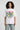 White oversized graphic t-shirt with colorful cartoon design and bold Peepers! text, worn with light blue jeans.