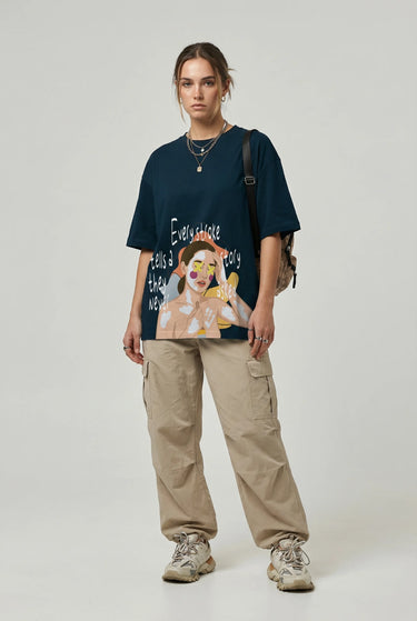 Navy oversized graphic t-shirt featuring colorful cartoon artwork, paired with beige cargo pants and sneakers.