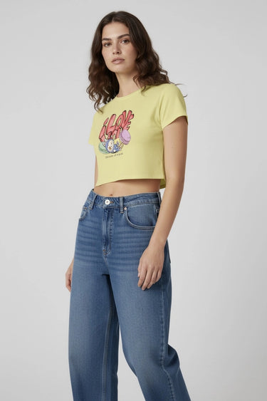 Yellow graphic crop top with colorful monster print, paired with high-waisted blue jeans. - LYVN