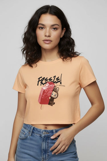 Peach graphic crop top with monster print and short sleeves on woman. - LYVN