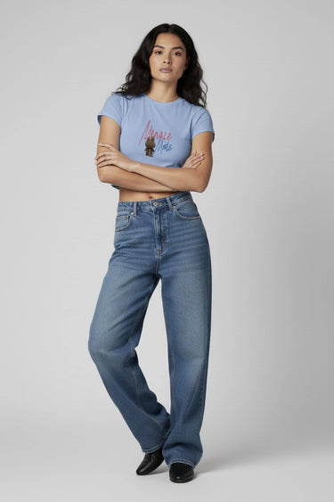 Light blue graphic crop top with colorful monster print worn with high-waisted wide-leg jeans. - LYVN