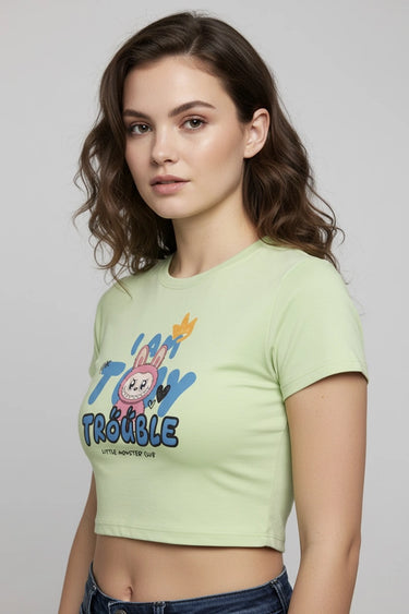 Light green graphic crop top with colorful monster print and "Tiny Trouble" text. - LYVN